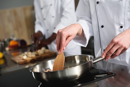 Close-up view of female chef cooking on frying pan