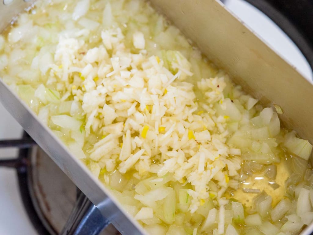メスティンにオリーブオイルを入れて中火で温め、玉ねぎを入れたら透明になるまで炒めて、ニンニクを加えてさらに2～3分炒めます。
