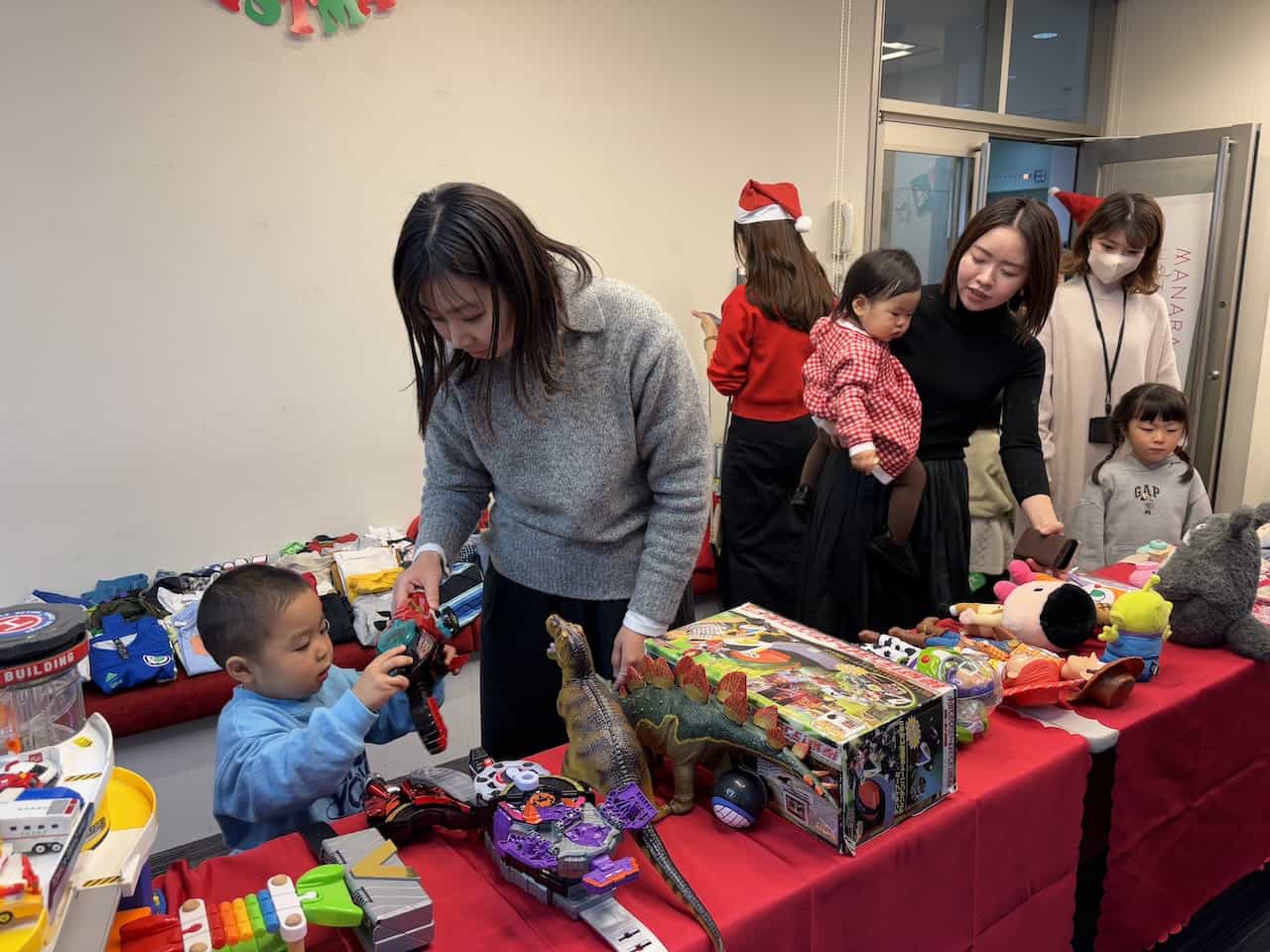 「継承クリスマス」イベントでおもちゃを選ぶ親子