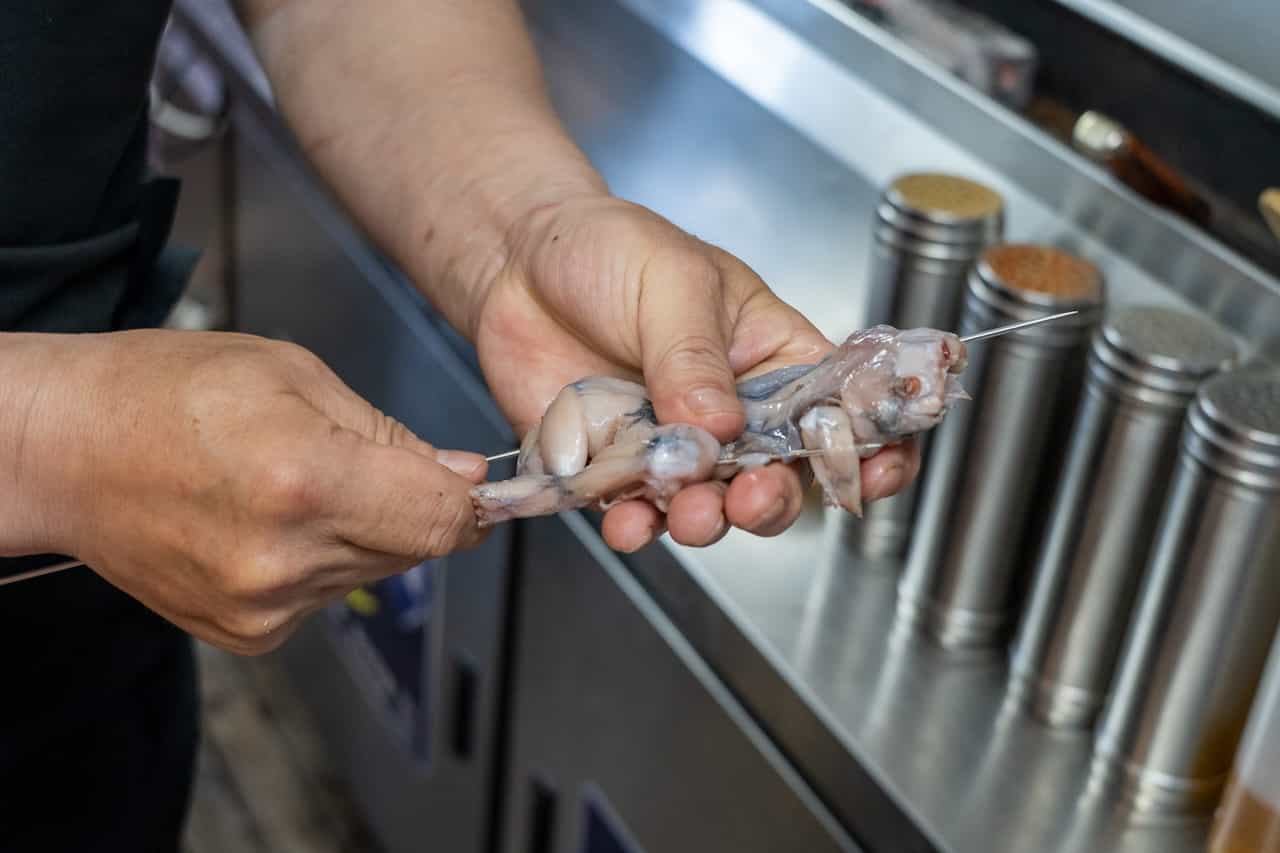 カエルの串焼きの調理場面